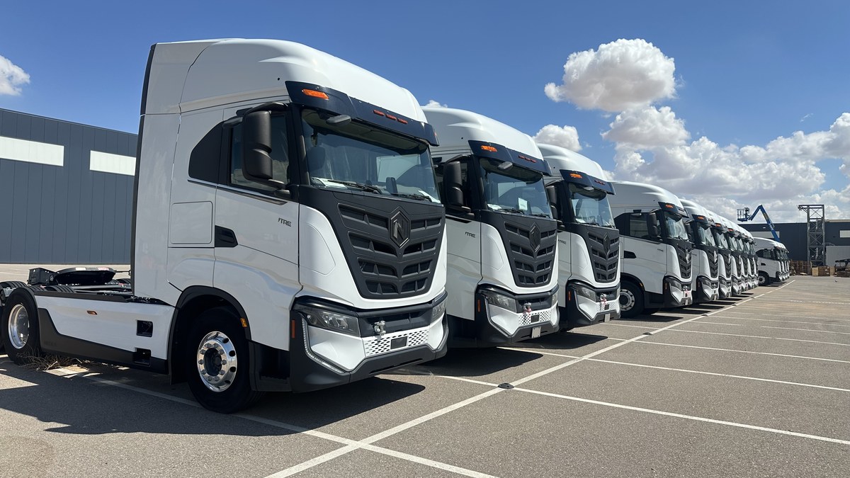 A row of white Nikola Tre BEV Class 8 electric tractors parked at the plant