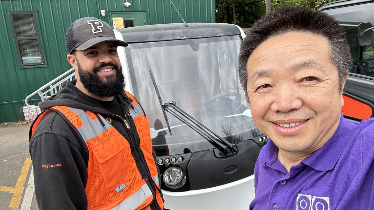 RoboStreet CEO with a Princeton University building services staff member beside a RoboStreet compact electric truck on campus